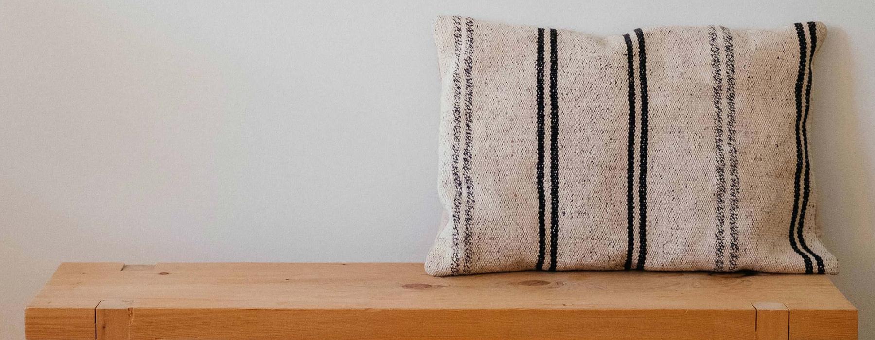 a wooden bench with a striped pillow on it